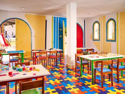 Sala de juegos colorida para niños con alfombras de rompecabezas y mesas pequeñas para actividades.