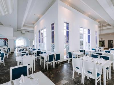 Jasna, przestronna restauracja z białymi i niebieskimi krzesłami i stołami w eleganckim stylu.