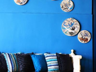 Weißes Sofa mit bunten Kissen vor einer blauen Wand mit dekorativen runden Wandplatten.