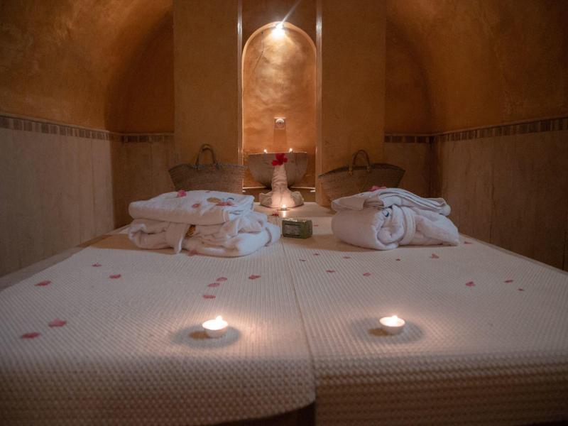 A cozy spa room with two massage tables, candlelight, and a warm atmosphere.