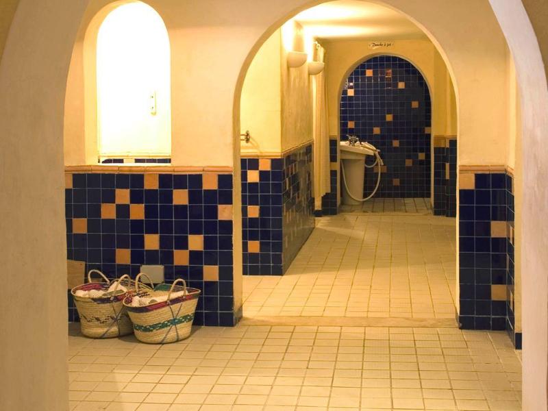 Heller Flur mit Bögen, blau-weißen Kacheln und zwei gefüllten Körben auf dem Boden.