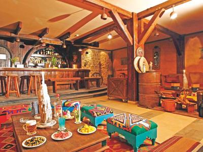 Gezellige hotelbar met houten meubels, een bar en diverse spellen op een tafel.