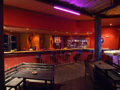 Gezellige bar met houten meubels, rode muren en indirecte verlichting.