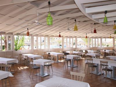 Helles, offenes Restaurant mit gedeckten Tischen und bunten Lampen an der Decke.