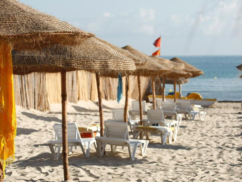 Strand met stroparasols en witte ligstoelen bij de zee