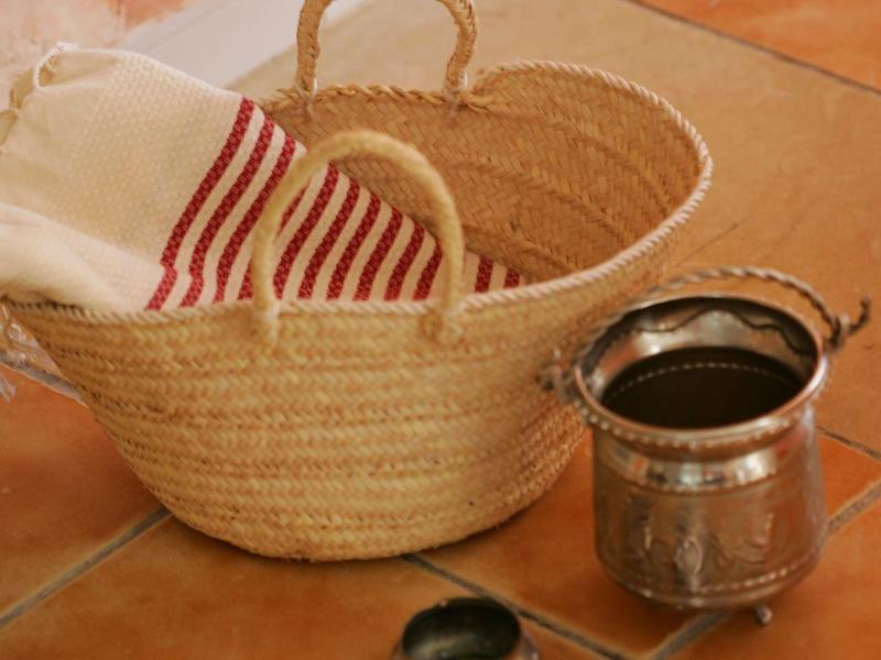 Gevlochten mand met handdoek en kaarsen op betegelde vloer voor ontspanning.