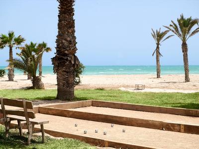 Beach with palm trees, sand, and a bocce court in the foreground