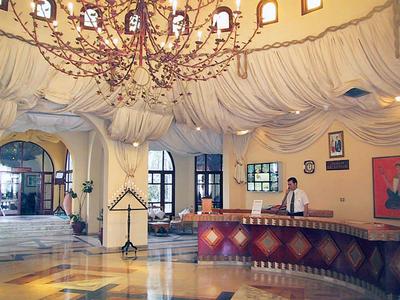 Luxusní hotelová lobby s velkým lustrem a recepčním pultem.