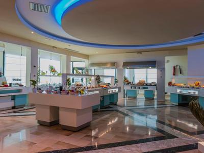 Moderní hotelová lobby s kulatým osvětleným stropem a světlými recepčními pulty.