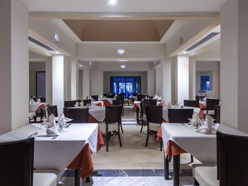 Elegantní restaurace s bílými ubrusy a tmavými židlemi v hotelu.