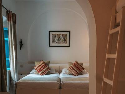 Schlafzimmer mit zwei Einzelbetten, Kissen, Bild an der Wand und architektonischem Rundbogen.