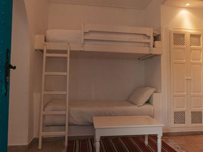 Ein Schlafzimmer mit einem weißen Etagenbett, einem weißen Tisch und einem gestreiften Teppich.