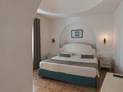 Schlafzimmer mit Doppelbett in neutralen Farben und bogenförmiger Decke in einem Hotelzimmer.