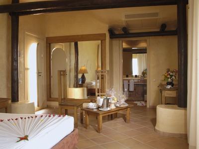 Przytulny pokój hotelowy z sofą, stołem i łazienką, jasno i ciepło oświetlony.