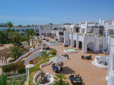 Complesso alberghiero con edifici bianchi, giardini, aree relax e vista sul mare sotto un cielo sereno.