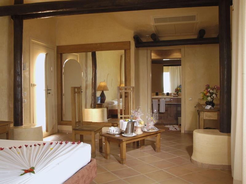 Przytulny pokój hotelowy z sofą, stołem i łazienką, jasno i ciepło oświetlony.