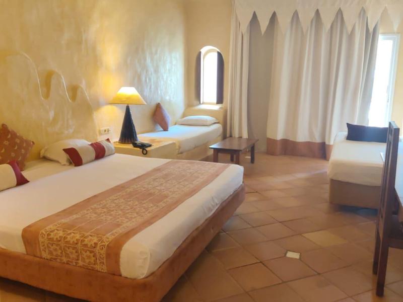 Przytulny pokój hotelowy z dużym łóżkiem, biurkiem i ciepłym oświetleniem.