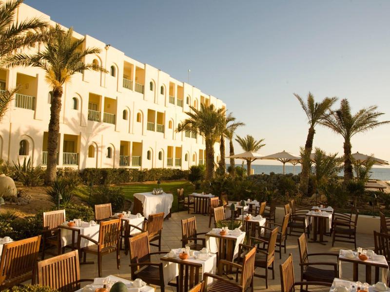 Außenbereich eines Hotels mit Terrassen und Blick aufs Meer bei Sonnenuntergang.