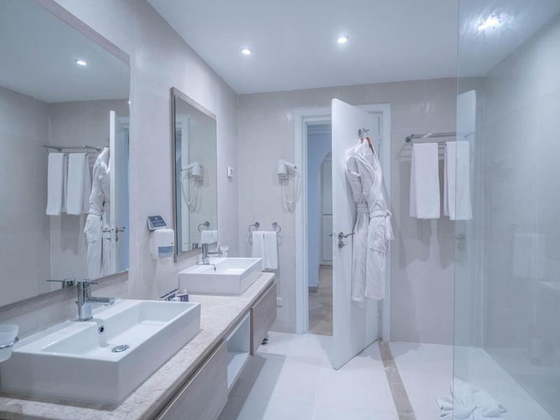 Modernes Hotelbadezimmer mit zwei Waschbecken und Bademänteln an der Tür.