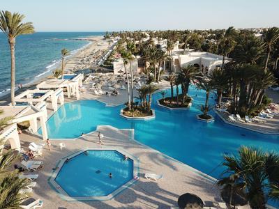 Grande piscina dell'hotel con palme e vista sulla spiaggia e sul mare con cielo sereno.
