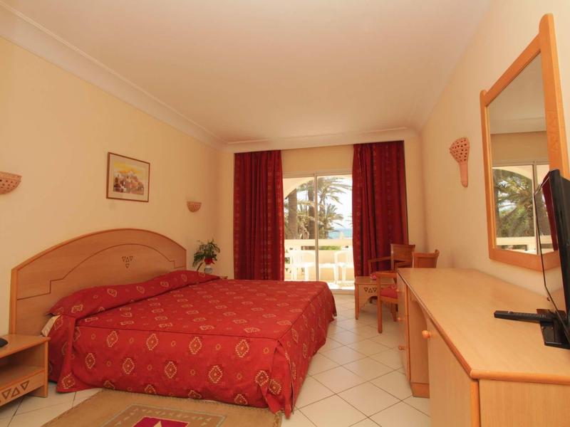 Jasny pokój hotelowy z podwójnym łóżkiem i widokiem na taras i ogród