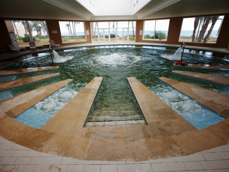 Wewnętrzne jacuzzi w hotelu z dużymi panoramicznymi oknami i dyszami do masażu wodnego.