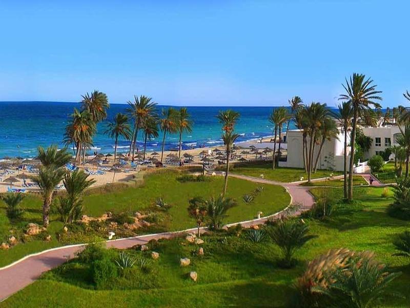 Vue d'une ville côtière avec parc, plage, mer et ciel bleu clair.