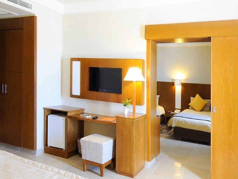 Modern eingerichtetes Hotelzimmer mit Holzvertäfelung, Spiegel, Fernseher und gemütlichem Bett.