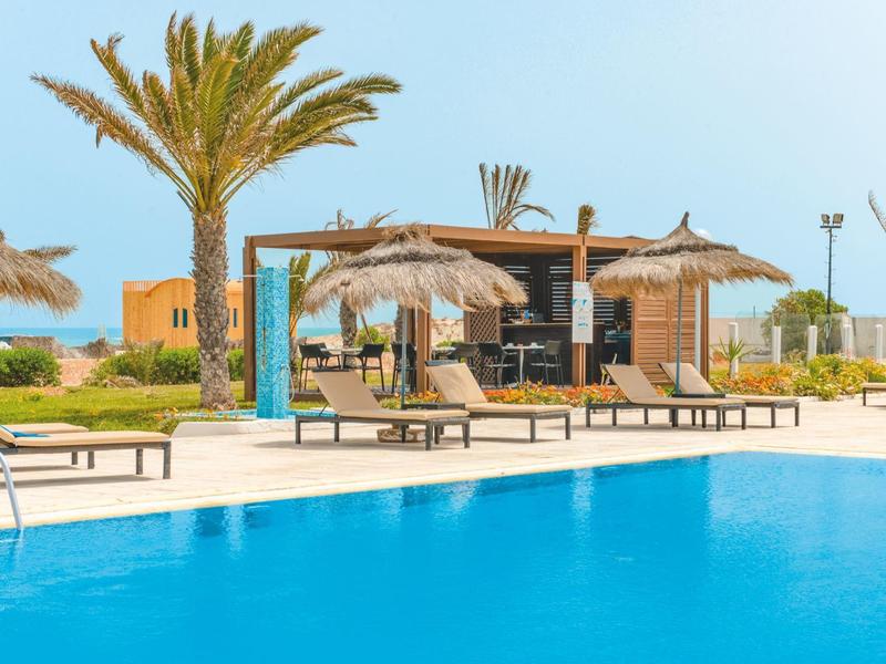 Venku bazén s lehátky a slunečníky v tropickém letovisku.