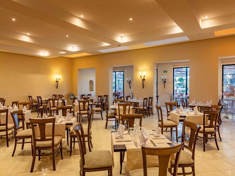 Großer, heller Speisesaal mit Holztischen und Stühlen, elegant gedeckt und warm beleuchtet.