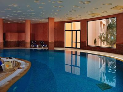 Piscina interna con finestre rotonde, sedia a sdraio e acqua calma in un hotel