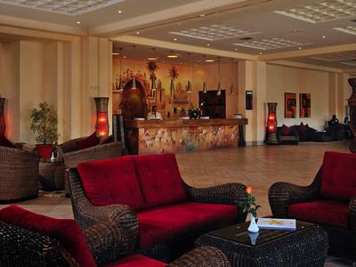 Accogliente area della hall dell'hotel con divani rossi e neri e reception sullo sfondo.