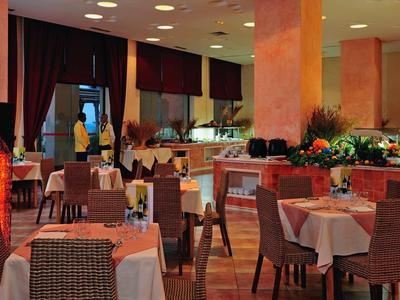 Ristorante elegante con tavoli apparecchiati, sedie e illuminazione decorativa in un'atmosfera calda.