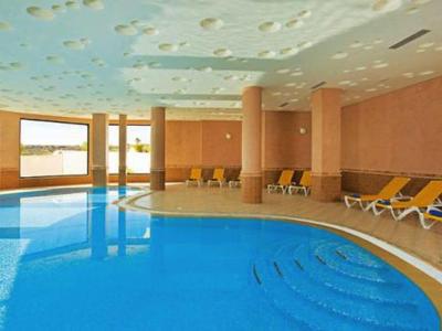 Area interna con grande piscina e lettini in una stanza luminosa e moderna.