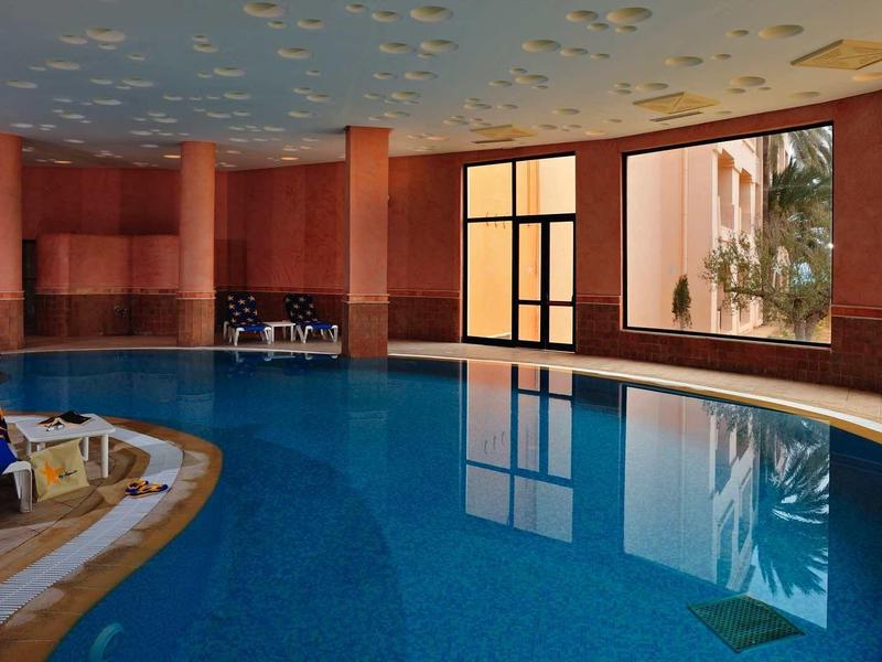 Piscina interna con finestre rotonde, sedia a sdraio e acqua calma in un hotel