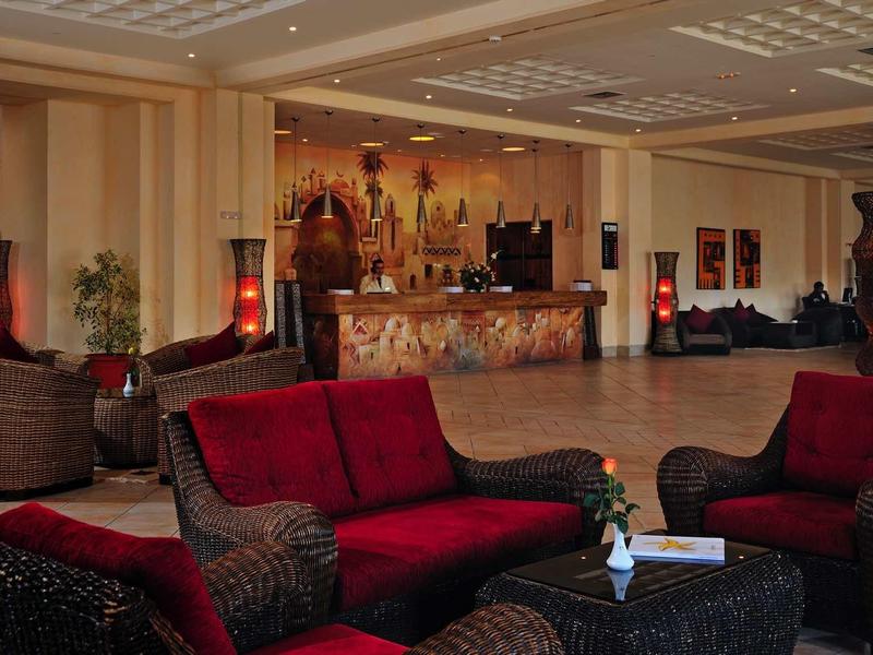 Accogliente area della hall dell'hotel con divani rossi e neri e reception sullo sfondo.