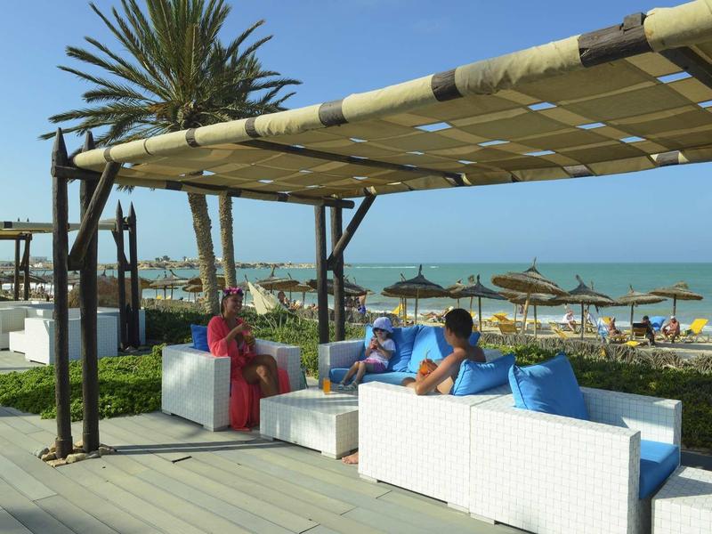 Accoglienti aree lounge con divani bianchi con vista sulla spiaggia e sul mare sotto una tenda