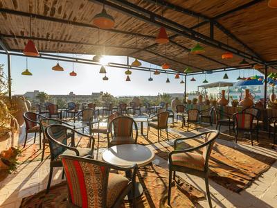 Offene Terrasse mit Stühlen und Tischen und Blick auf die Stadt bei Sonnenuntergang