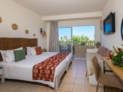 Camera d'hotel luminosa con due letti, balcone e vista sul verde.