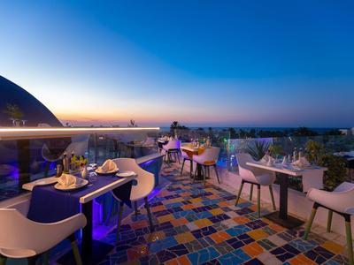 Terrazza panoramica con pavimento colorato, tavoli e sedie al tramonto con vista lontana