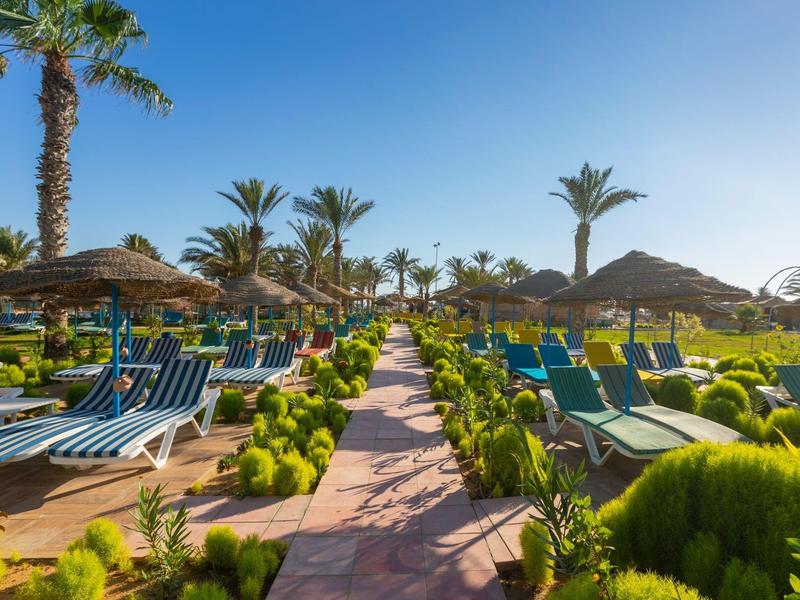 Sentiero tra lettini e palme in un giardino di hotel soleggiato