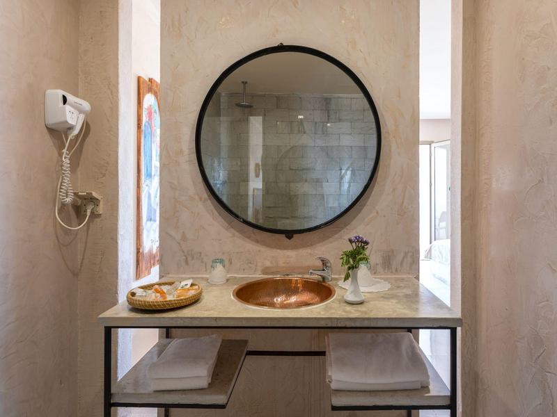 Bagno moderno con specchio rotondo, lavabo e due asciugamani sotto la mensola.