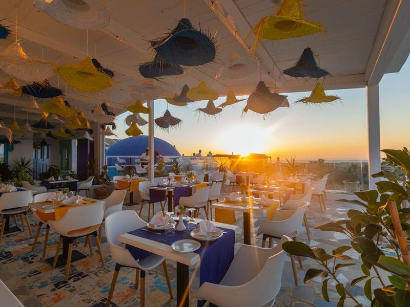 Terrazza del ristorante con tavoli apparecchiati e vista mare al tramonto
