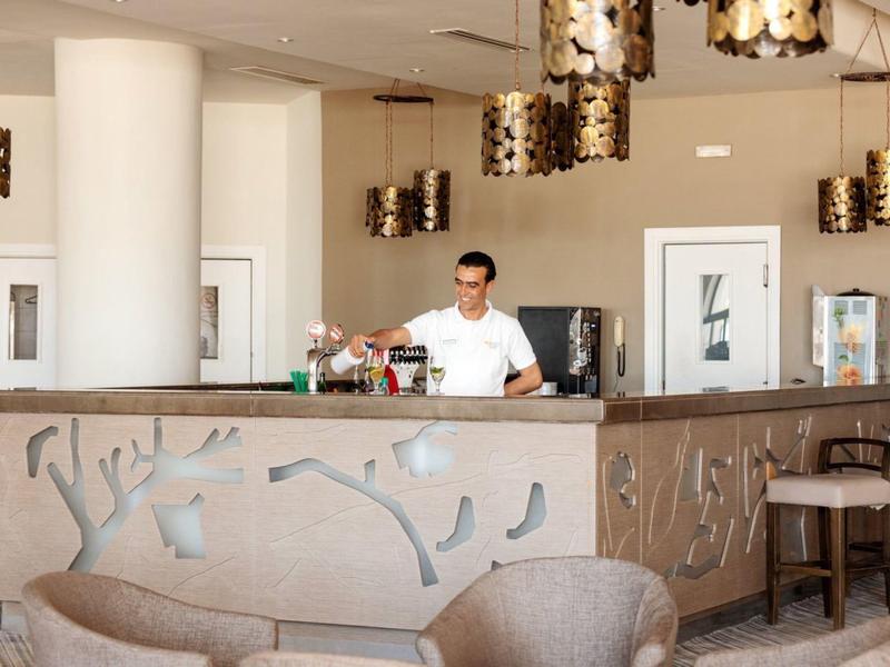 Moderner Barbereich mit hellen Holzmöbeln, dekorativen Lampen und gemütlichen Sitzgelegenheiten.