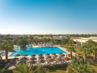 Großer Poolbereich mit Liegestühlen und Sonnenschirmen in einem tropischen Resort bei klarem Himmel.