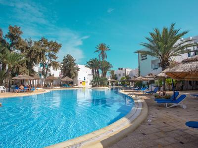 Ein großer Außenpool mit blauen Liegestühlen und Palmen unter blauem Himmel.