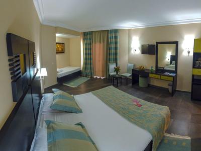 Camera d'hotel confortevole con letto grande, scrivania, sedie e finestra con tende.