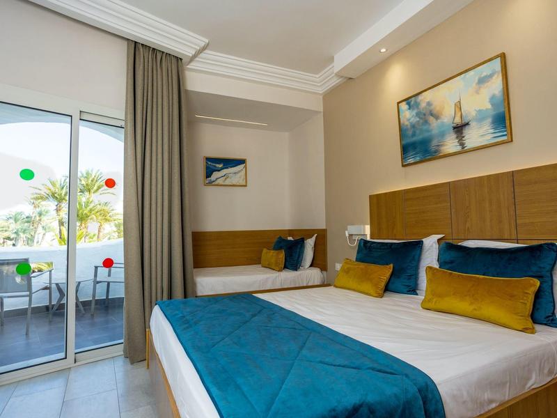 Camera d'hotel moderna con letto matrimoniale e singolo, balcone e vista mare.