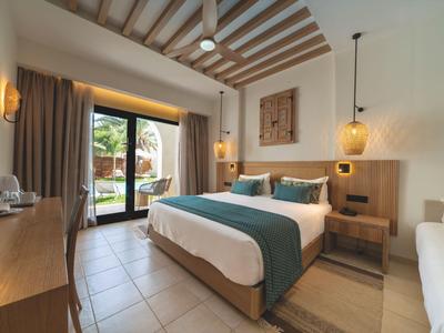 Moderner Hotelzimmer mit Doppelbett, Holzakzenten und Zugang zu einem Garten.