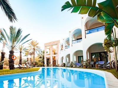 Modernes Hotel mit Pool, Palmen und weißem Gebäude unter blauem Himmel